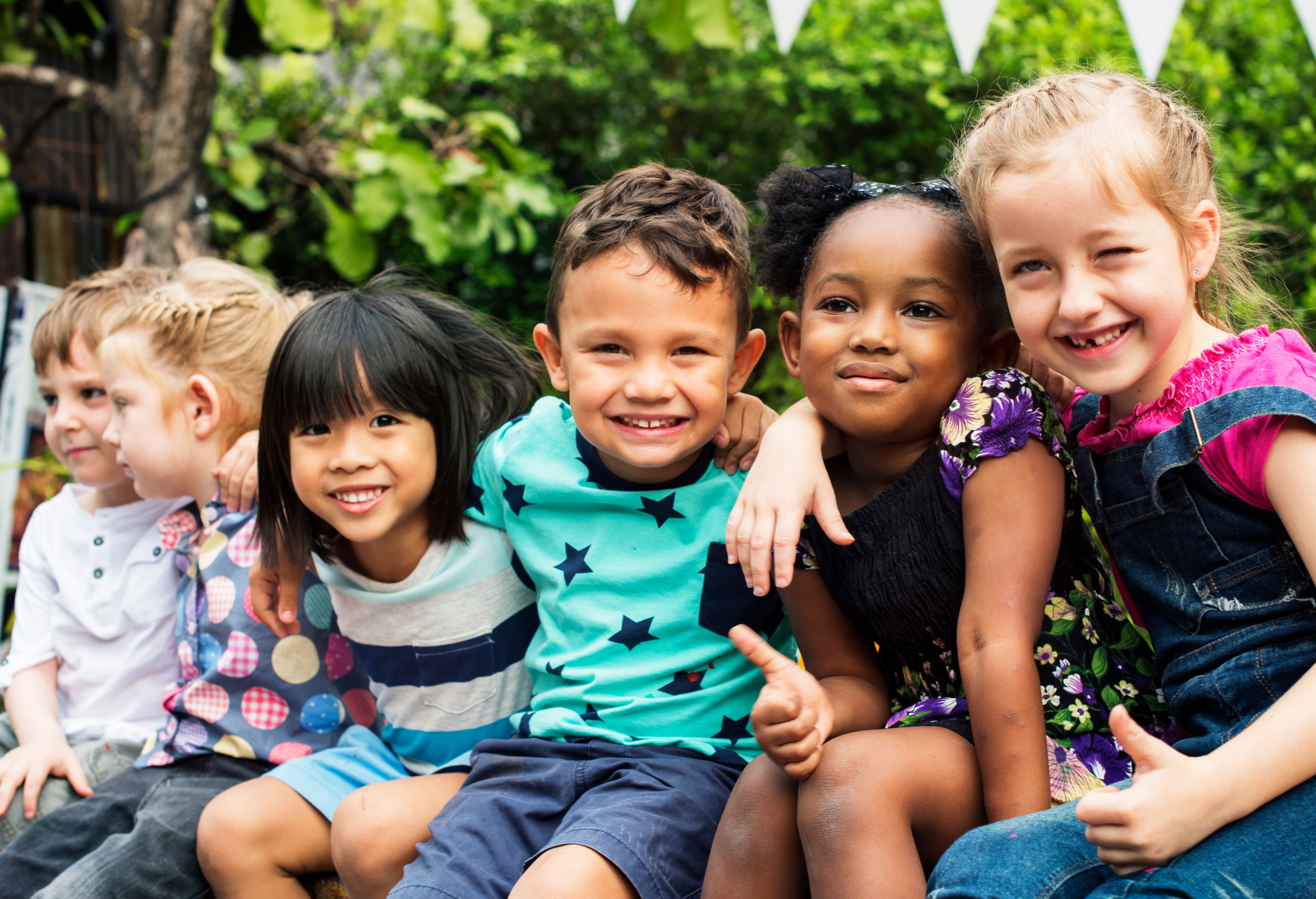 Bambine e bambini seduti all'aperto
