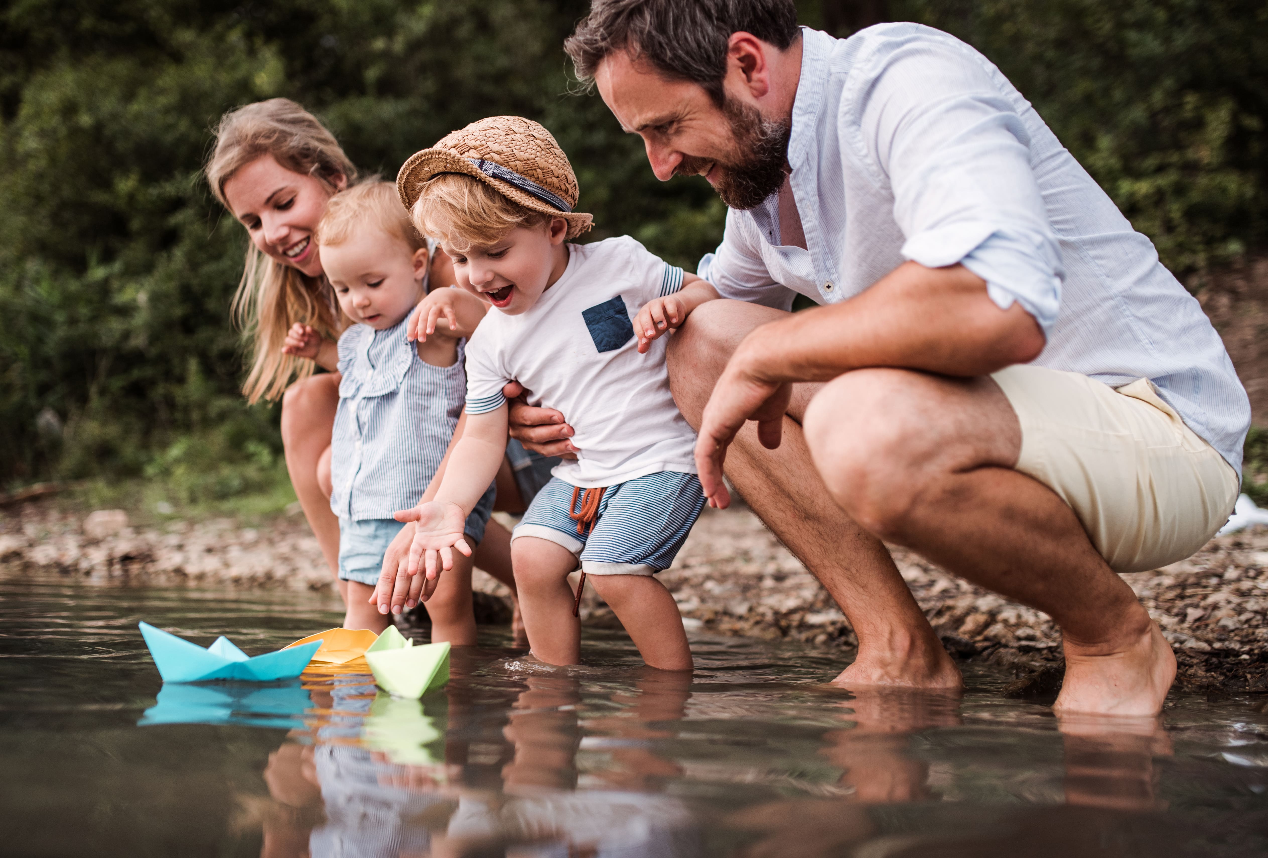 Una famiglia gioca con le barchette di carta in un torrente